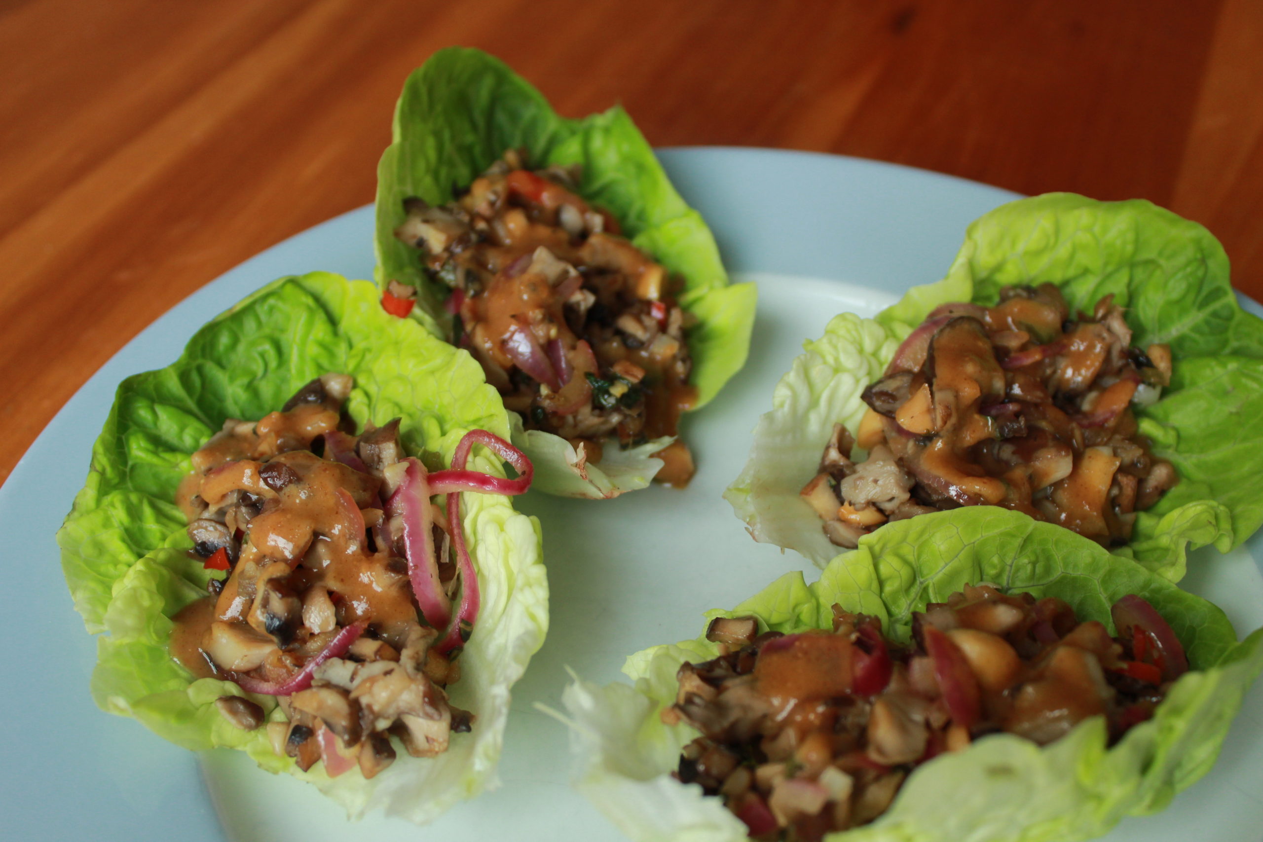 vegan mushroom larb lettuce boats on a white plate