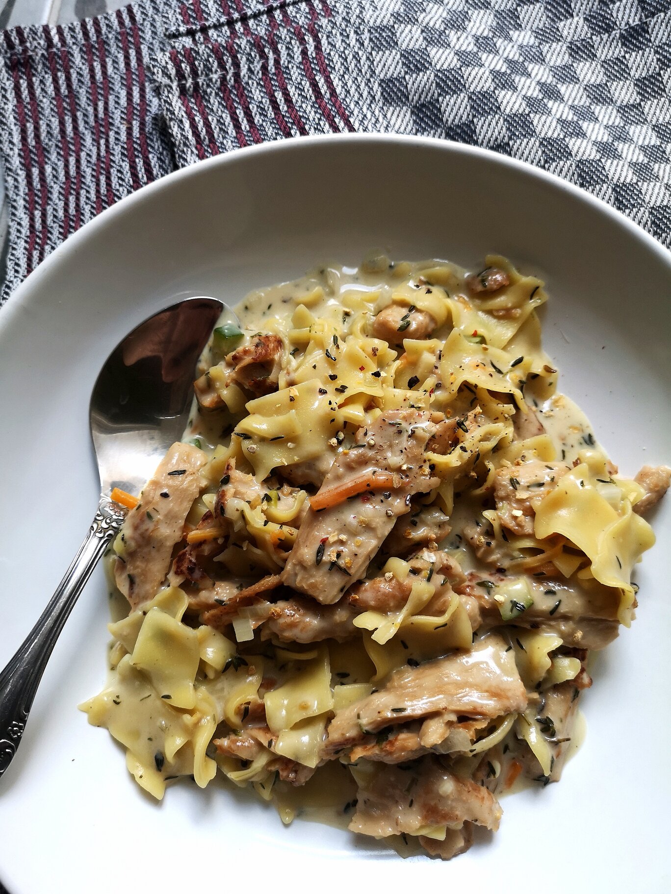 vegan lemon pasta in a white dish next to a silver spoon