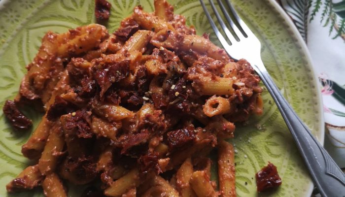 sundried tomato walnut pasta on a plate with a fork