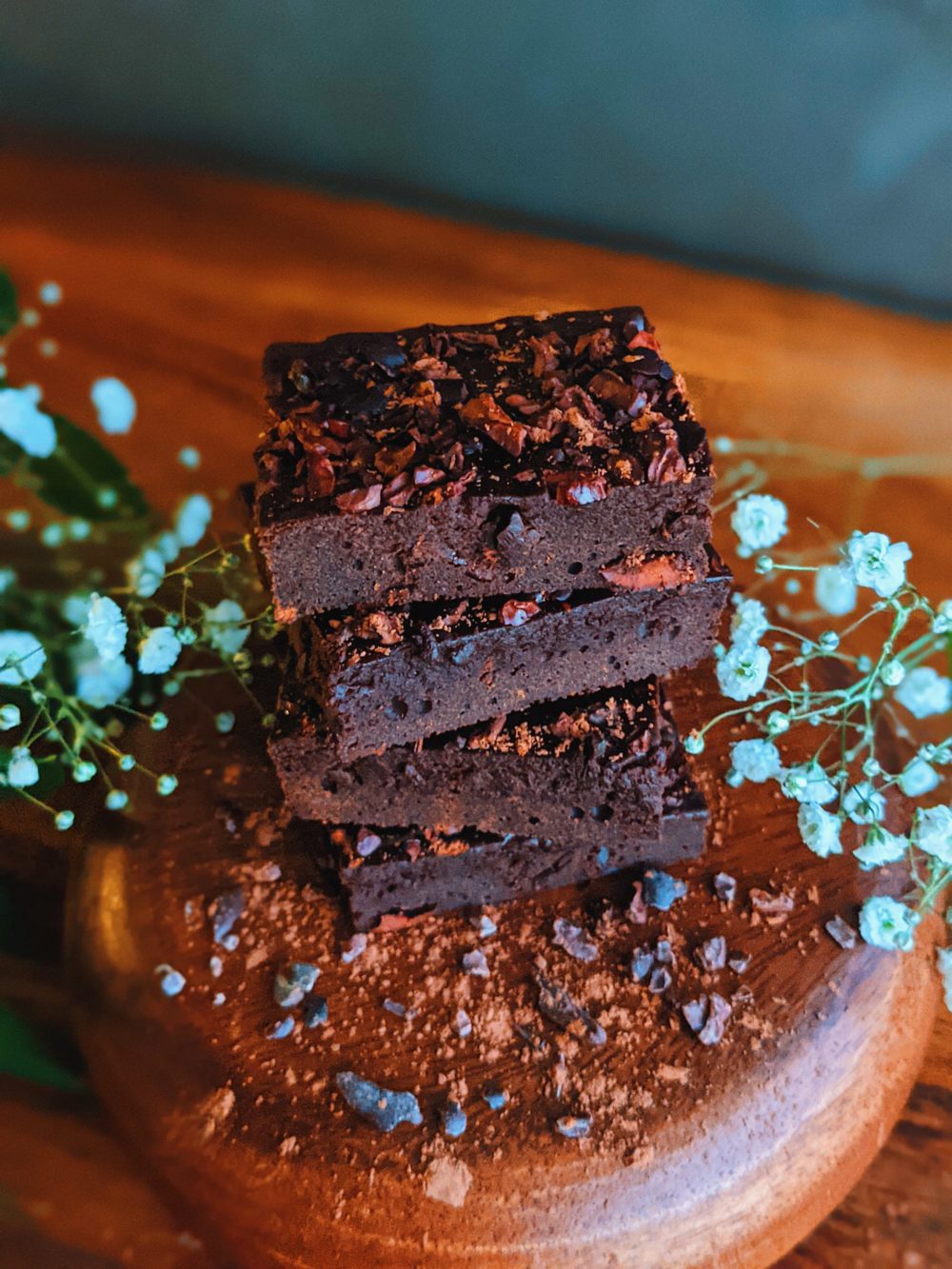 raw cacao brownies on a wooden table with white flowers