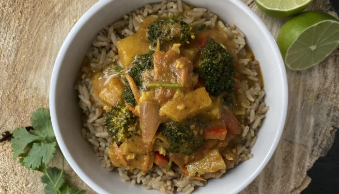 pineapple curry in a white bowl next to limes and parsley