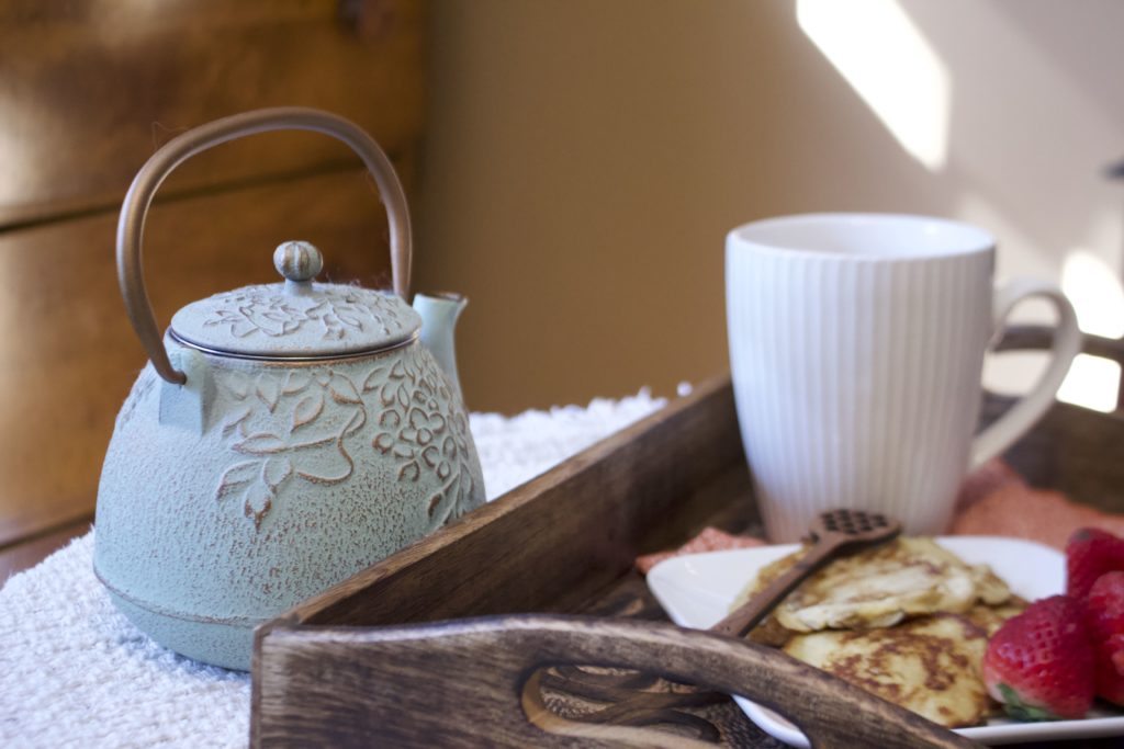 tea kettle with pancakes on wooden tray