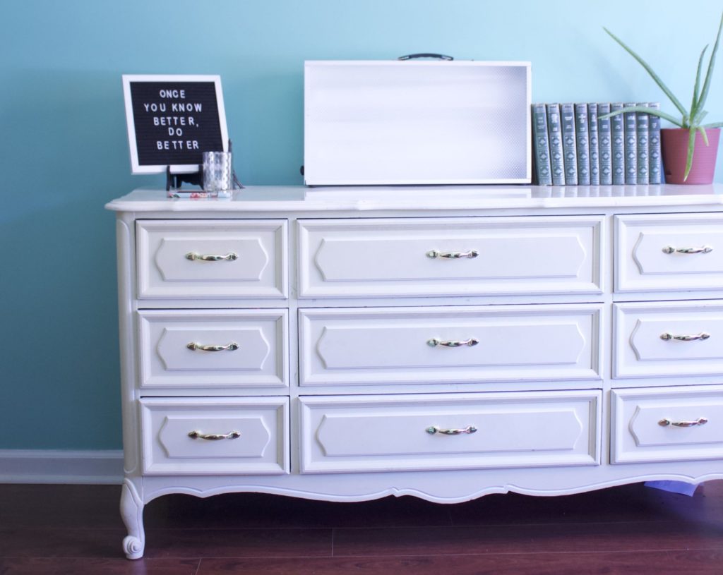 white dresser with sun lamp, books, and aloe plant
