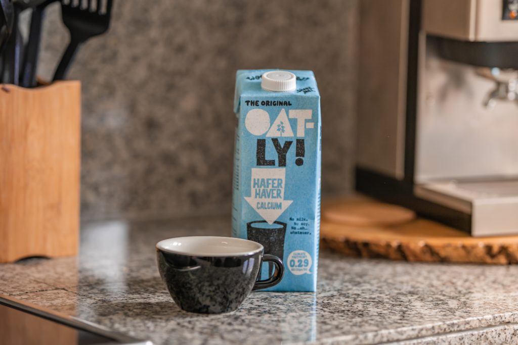 A carton of Oatly oat milk on a kitchen counter