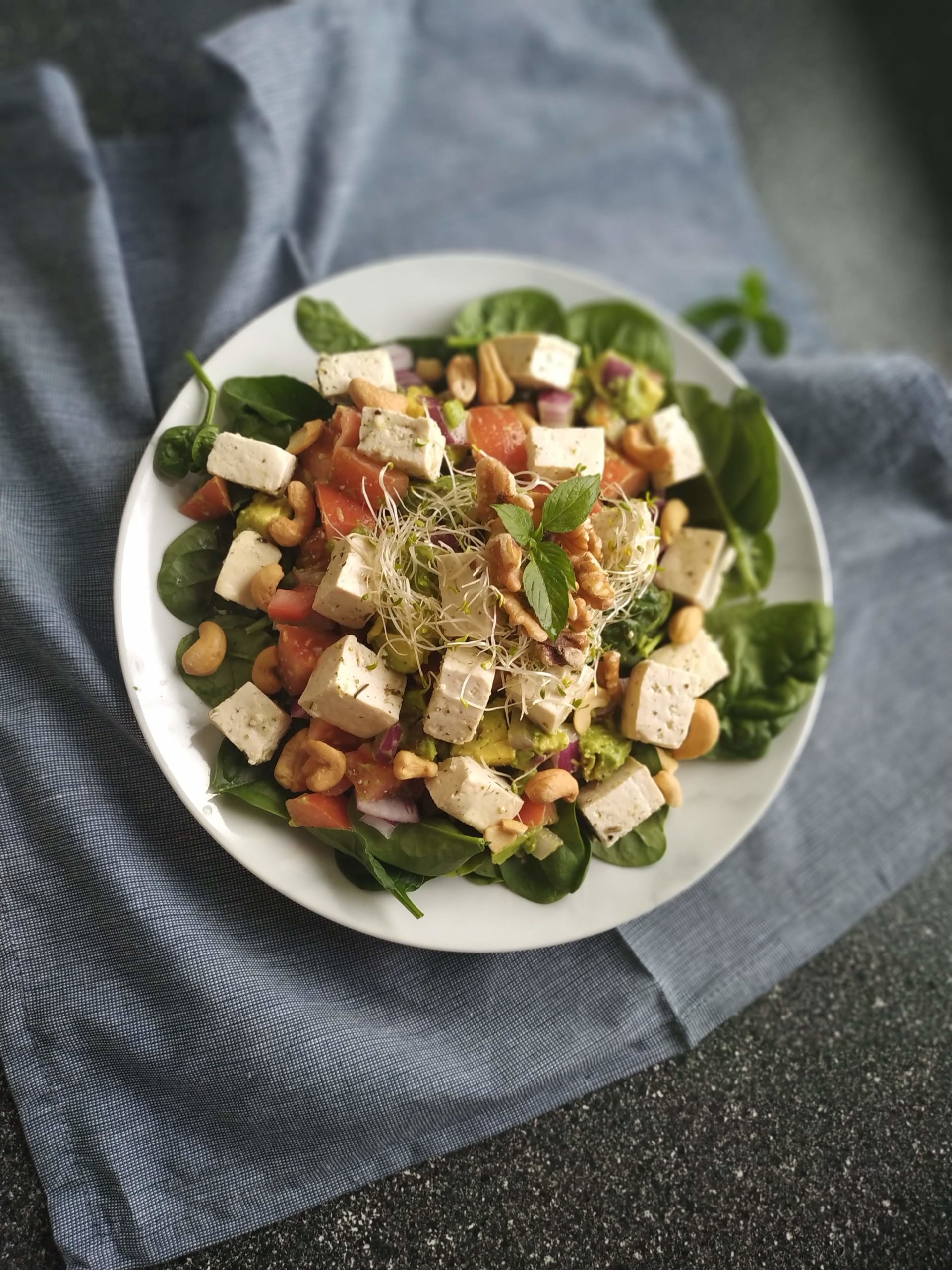 tofu feta salad on a white plate on a gray dish towel