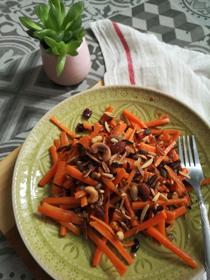 moroccan carrot salad on a green plate next to a plant