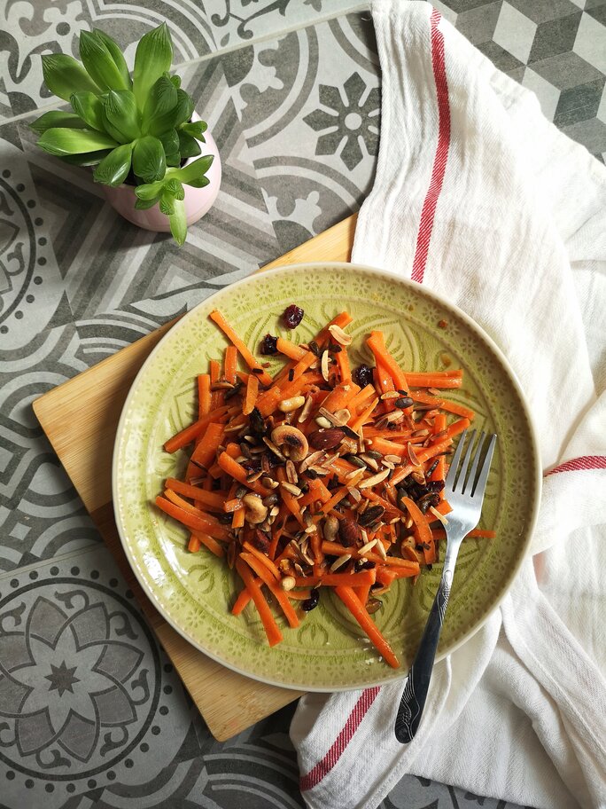 moroccan carrot salad on a green plate next to a plant