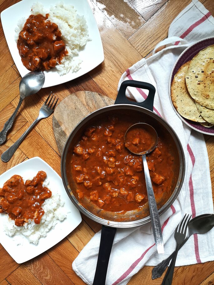 vegan kashmiri rogan josh in a pot and on a plate with white rice on a table