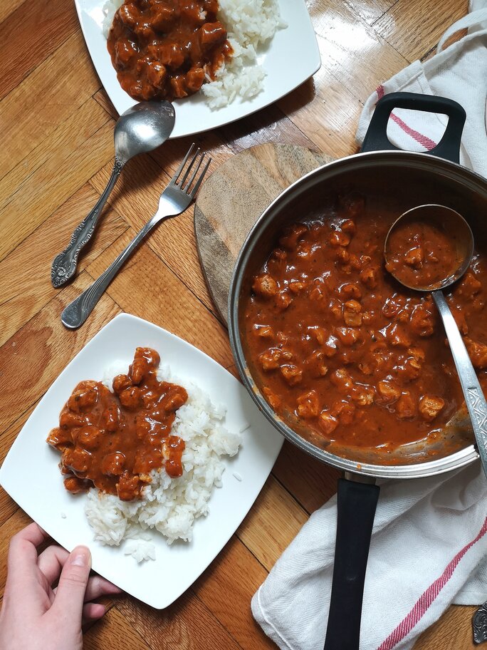 vegan kashmiri rogan josh in a pot and on a plate with white rice on a table