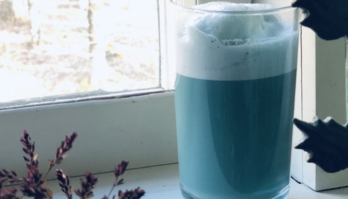 azure latte in a glass on a white windowsill