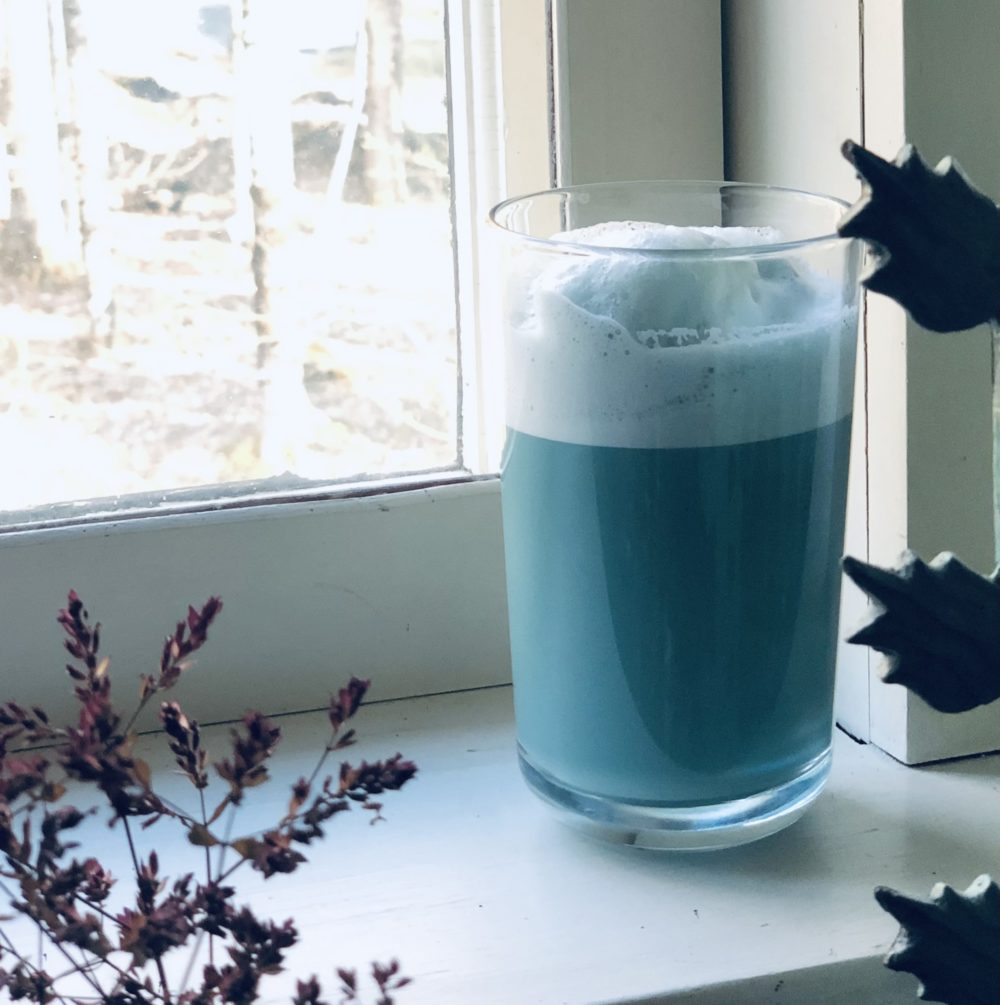 azure latte in a glass on a white windowsill