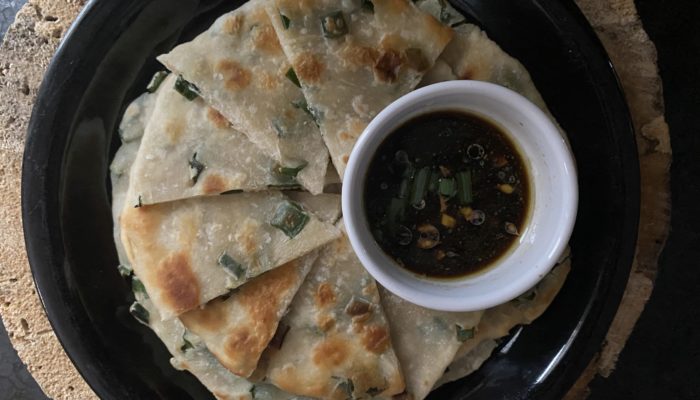 scallion pancakes with ginger soy sauce on a dark plate