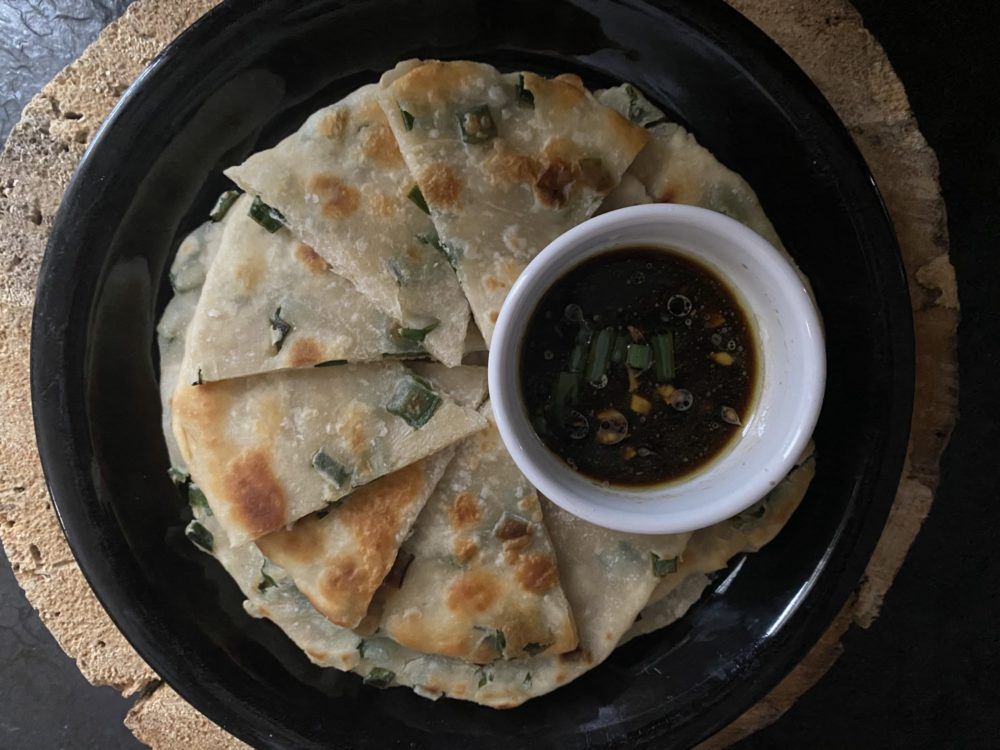 scallion pancakes with ginger soy sauce on a dark plate