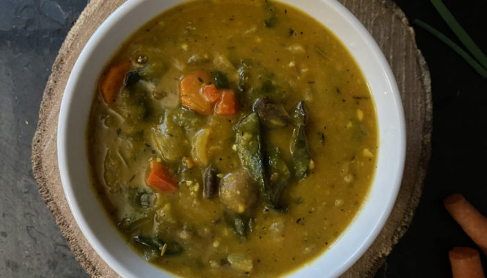 vegan haitian pumpkin soup in a white bowl against a brown and black background