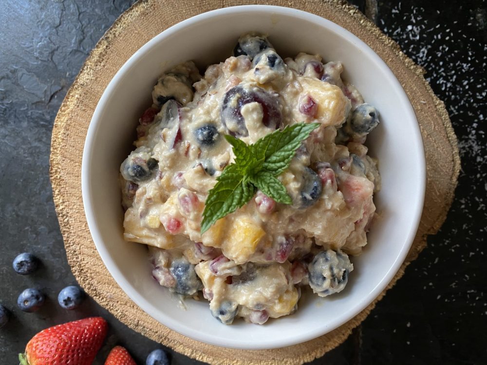 vegan ambrosia salad in a white bowl against a brown and black background