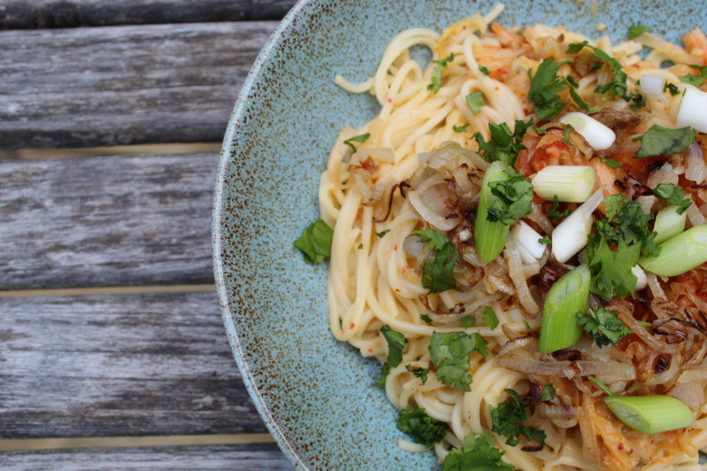 kimchi alfredo linguine in a dish against a wooden table