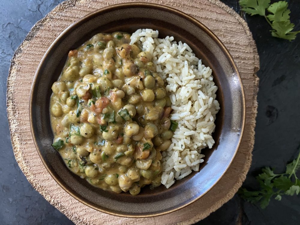 caribbean coconut pumpkin pigeon peas with rice in a brown bowl against a brown and black background