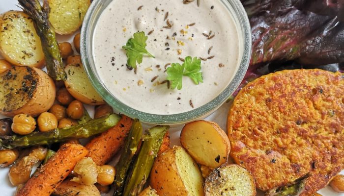 split pea steak with vegetables and tahini yogurt sauce on a white plate