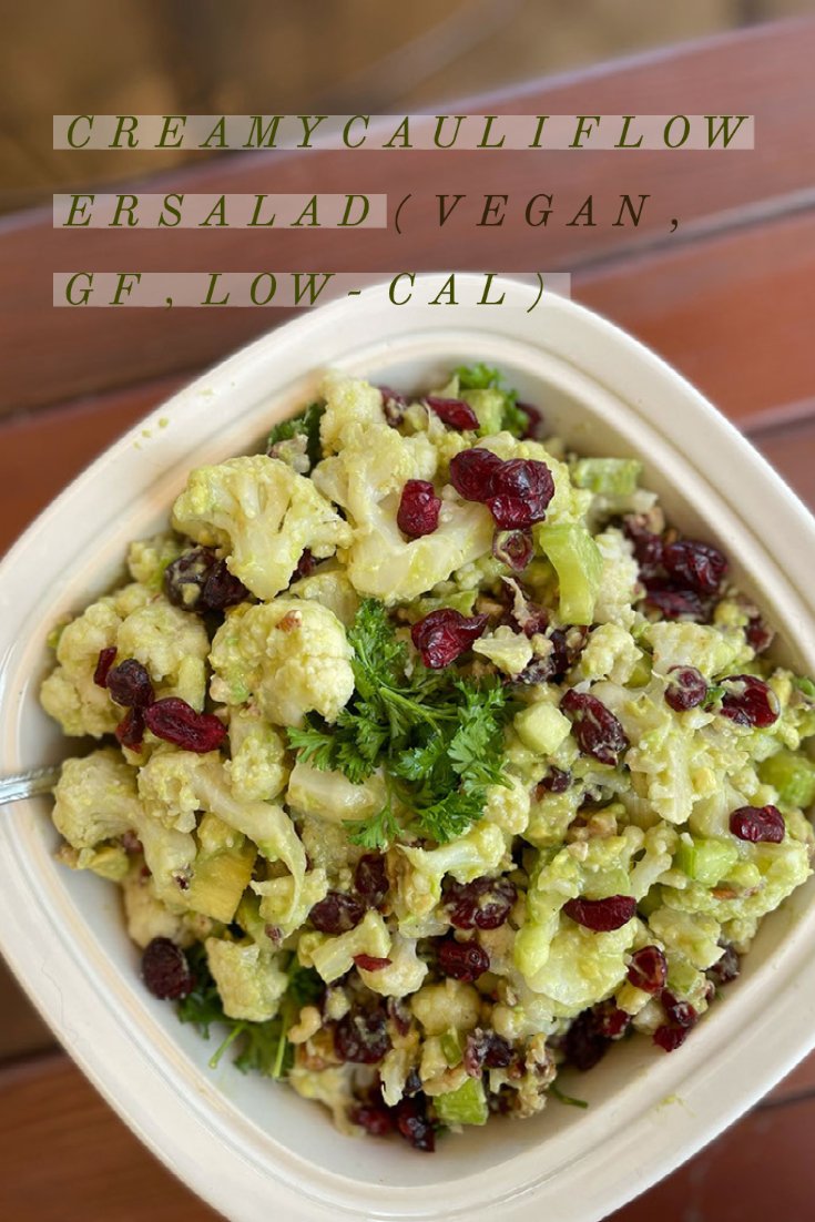 creamy cauliflower salad in a white dish on a table with overlayed caption