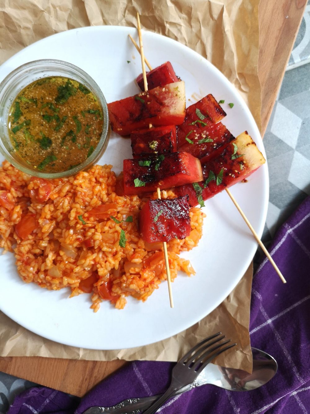 grilled watermelon and turkish rice on a white plate next to silverware