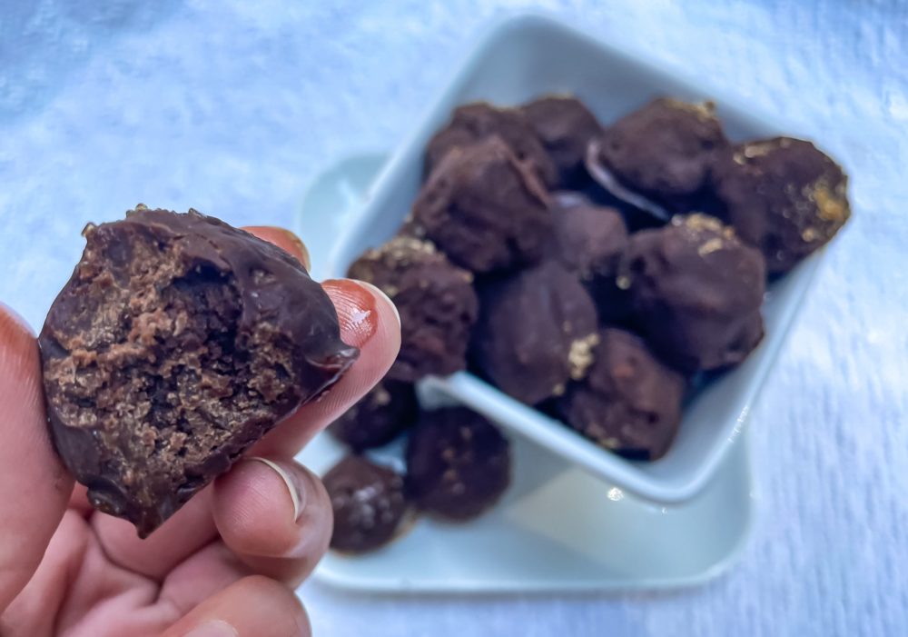 Close up of bitten truffle with chocolate truffles in the background