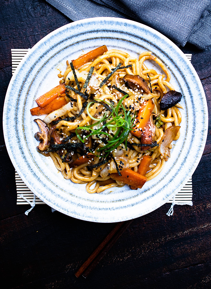 yaki udon on a striped plate with a dark background