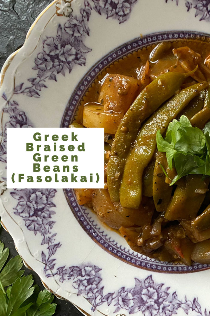greek braised green beans on a plate with overlayed caption