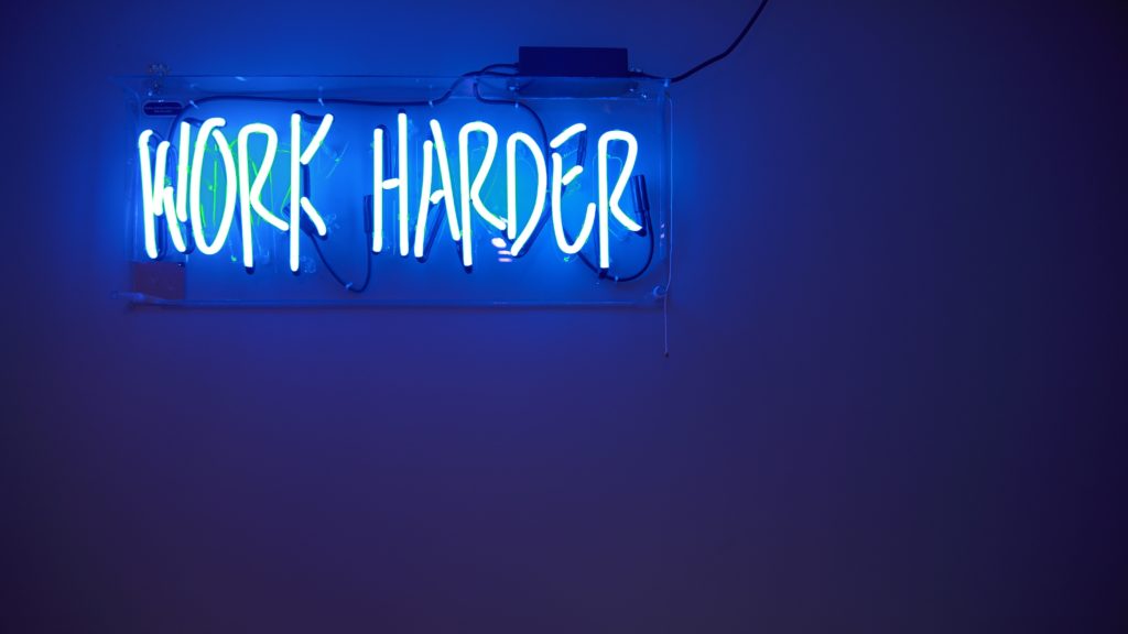 Neon sign that reads 'work harder'