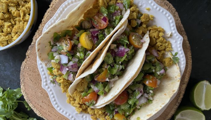 chickpea scramble tacos on a white plate against a black and brown background