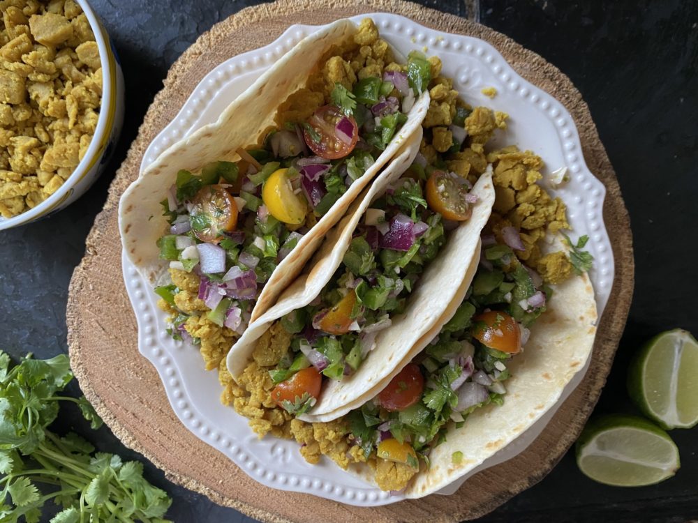 chickpea scramble tacos on a white plate against a black and brown background