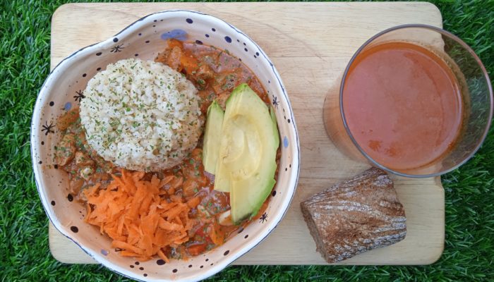 vegan stew and a beverage on a wooden tray in the grass