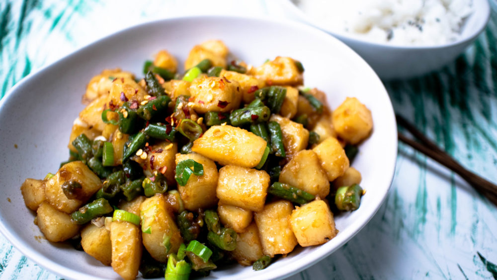 green beans and potatoes in garlic sauce in a white bowl