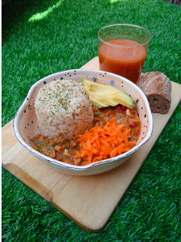 a bowl of stew and a beverage on a tray in the grass