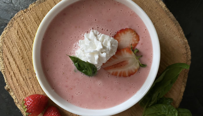 vegan strawberries and cream in a white bowl against a brown and black background