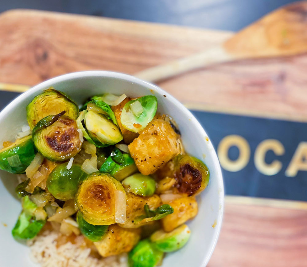 brussel sprouts on an eat local cutting board in a bowl with rice