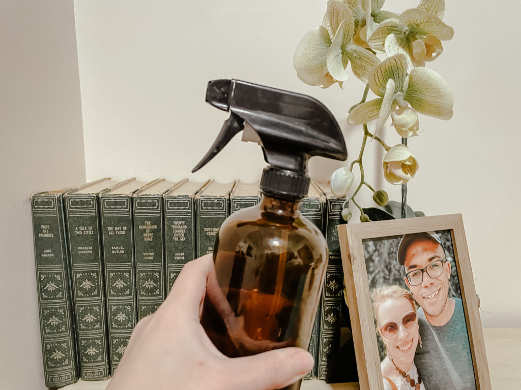 hand holding spray bottle in front of books