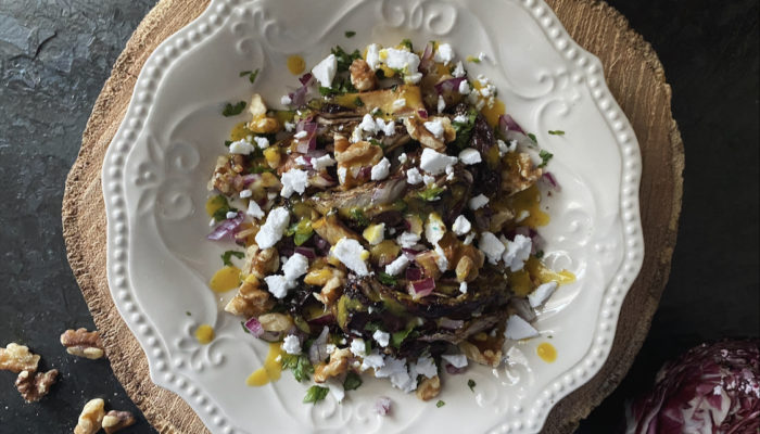 radicchio salad on a white plate against a brown and black background
