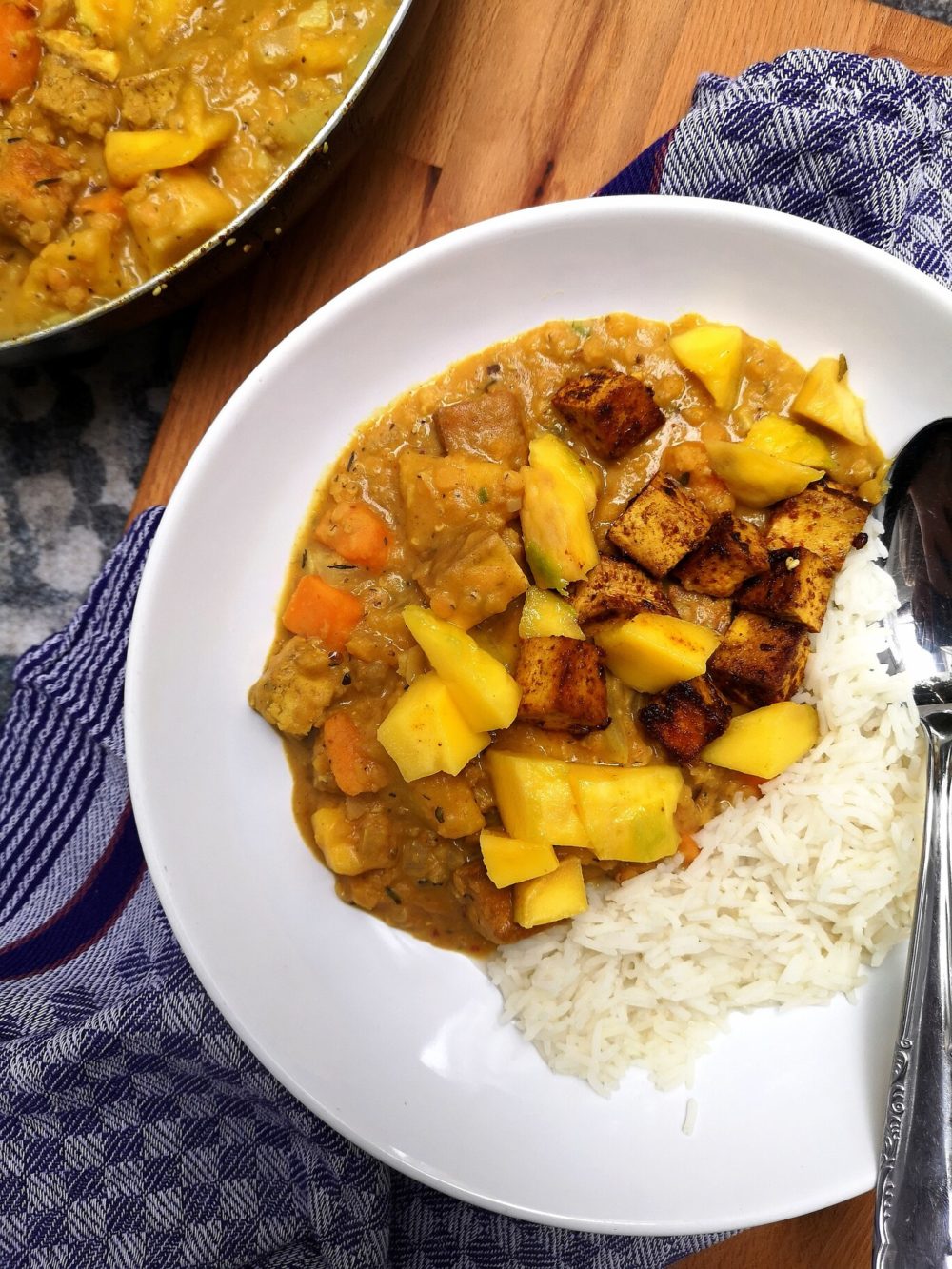 jamaican mango stew on a white plate with spoon
