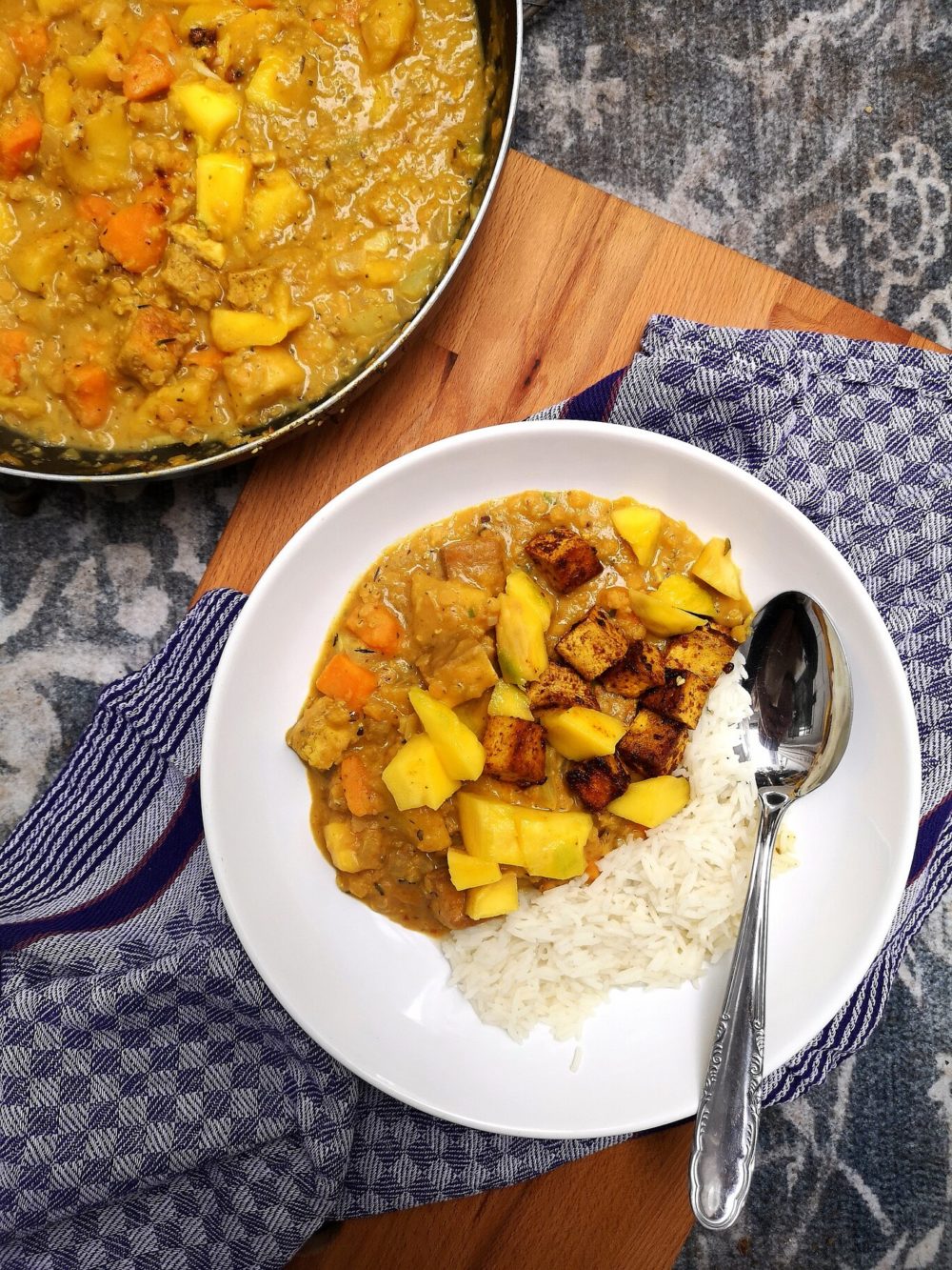 jamaican mango stew on a white plate with a spoon