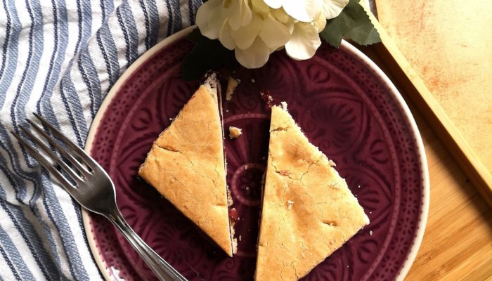 sour cherry pie on a plate with a fork next to a white flower