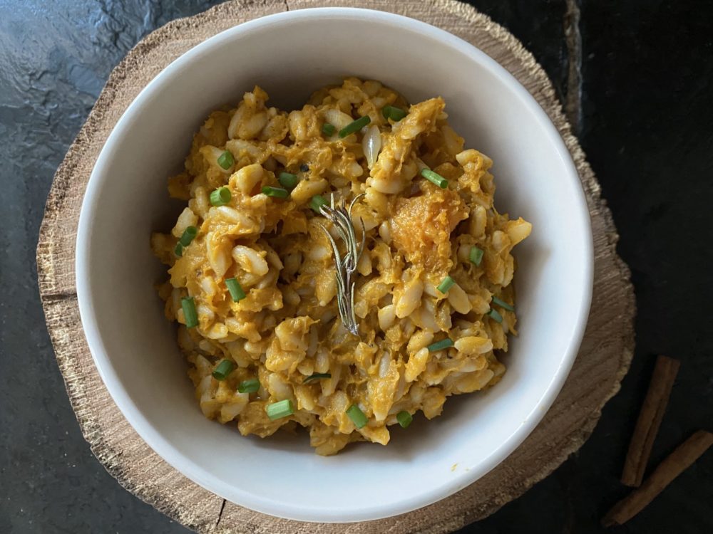 butternut risotto in a white bowl with brown and black background