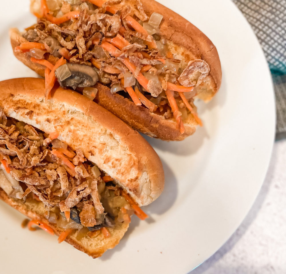 two hot dog buns with carrot mushroom slaw on white plate