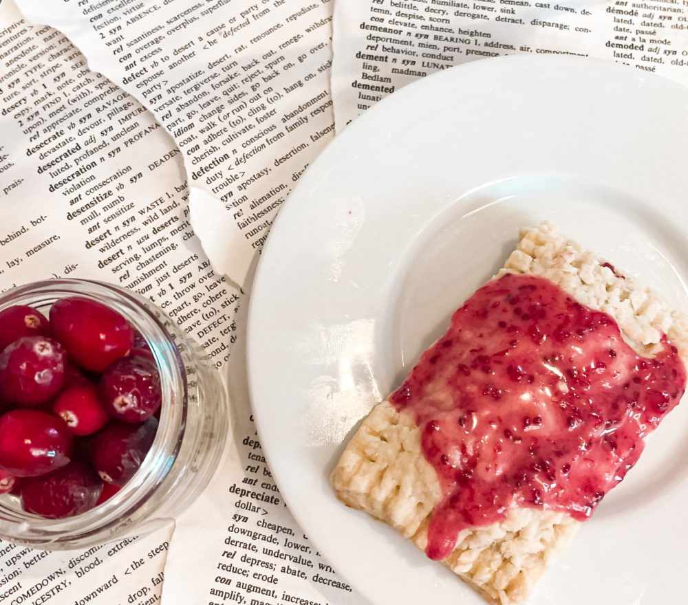 pop tart next to bowl of cranberries on book pages