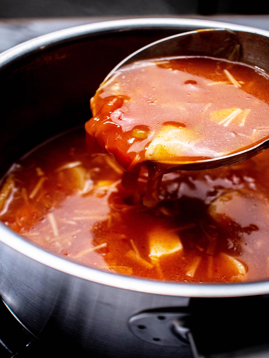 a ladle scooping tofu soup in a pot