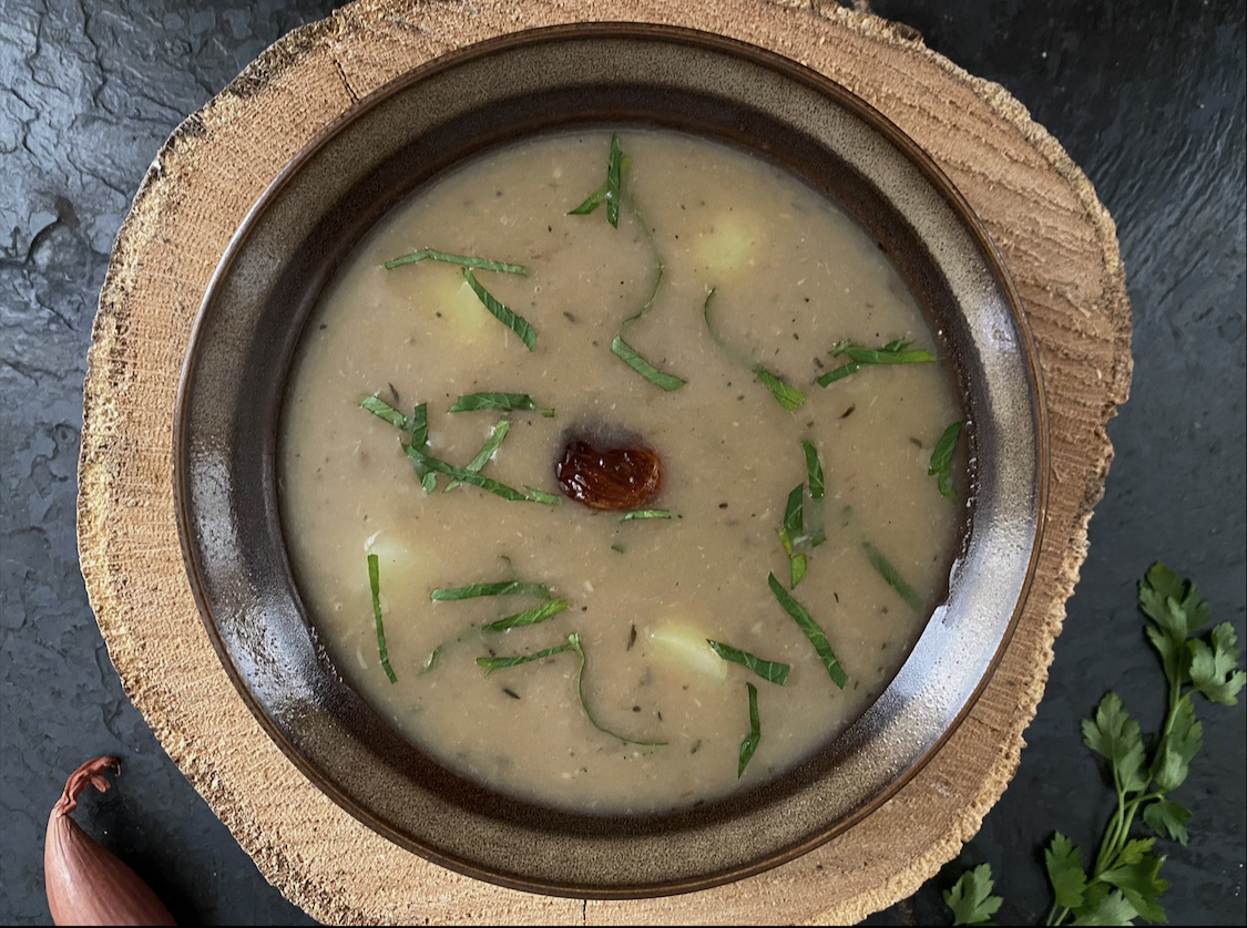 creamy roasted garlic soup in a dish agaisnt a dark background