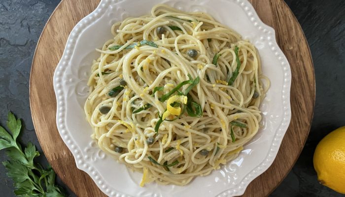 lemon caper pasta in a white dish against a dark background