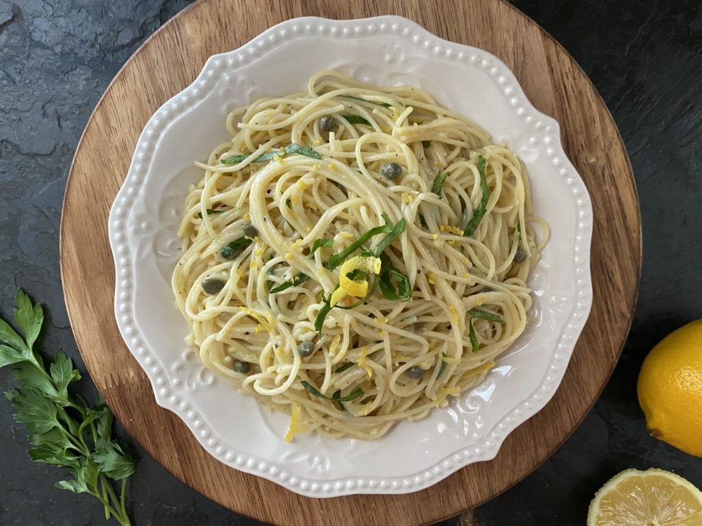 lemon caper pasta in a white dish against a dark background
