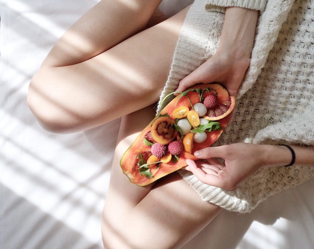 woman holding papaya filled with fruit