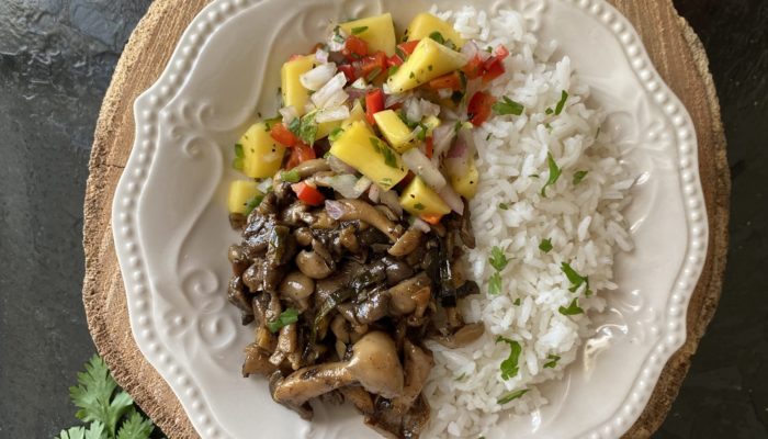 jerk mushrooms and mango salsa on a white plate against a brown and black background