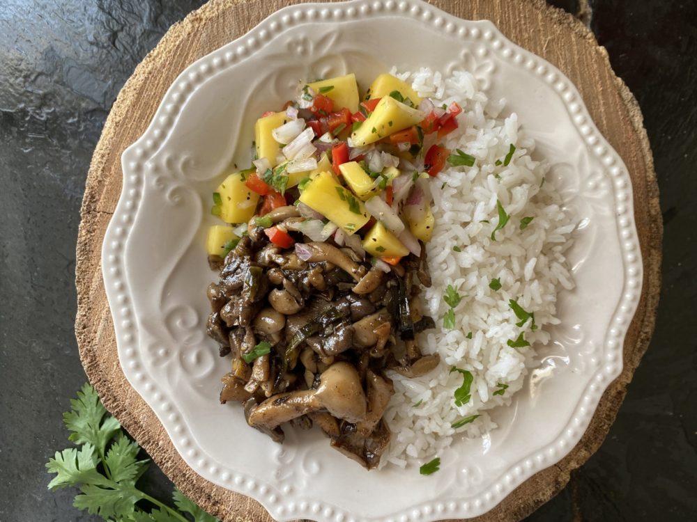 jerk mushrooms and mango salsa on a white plate against a brown and black background